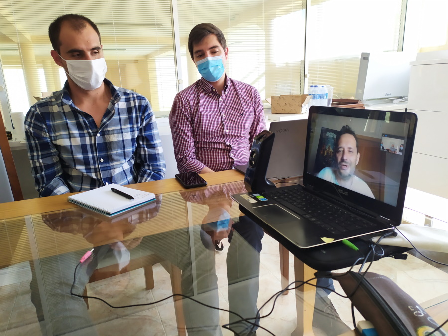 Mesa de reuni&atilde;o com 3 intervenientes, dois sentados e um via videoconfer&ecirc;ncia - sess&atilde;o A2B