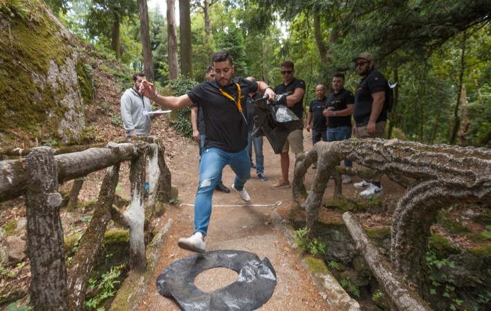 Homem a correr numa ponte na floresta (atividade de Team building) seguido de outras pessoas.