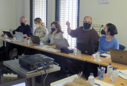 5 parceiros reunidos numa mdesa de trabalho a debater.